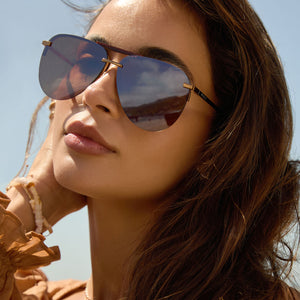 lifestyle- female at the beach wearing diff eyewear featuring the tahoe aviator sunglasses with a sequoia tortoise frame and brown gold flash lenses angled view