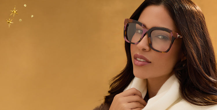 Young woman wearing pink glasses leaning her head against her hand as the sunlight through the window hits her face